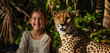 A girl is sitting next to a majestic cheetah in a background of lush vegetation, grinning broadly as they both turn to look curiously at the camera