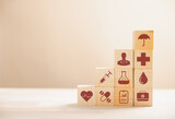 Fototapeta  - Wooden cubes stacked in a pyramid shape, embodying the healthcare and insurance concept. Atop, a medical insurance icon signifies protection. Blue background offers copyspace for Health Insurance idea