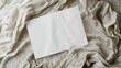A blank white paper rests on a textured, crumpled fabric