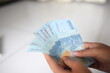 .A woman's hand holds fifty thousand Indonesian notes for the Eid al-Fitr holiday