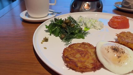 Wall Mural - A plate of food with a side of coffee. The plate has a variety of food items including a potato, a piece of fish, and a salad. The coffee is in a cup on the table