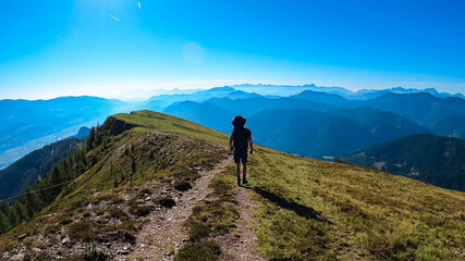 Wall Mural - Man with baby carrier on hiking trail with scenic view of magical mountain peaks Karawanks and Julian Alps seen from Goldeck, Latschur group, Gailtal Alps, Carintha, Austria. Austrian Alps in summer