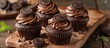 Rich and moist chocolate cupcakes with chocolate frosting beautifully displayed on a wooden cutting board.