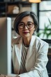 © Andrii Zastrozhnov - A portrait of a Asian businesswoman in a modern office, confidently working on her laptop.