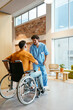 © BONNINSTUDIO/Stocksy - Male nurse and man in wheelchair greeting each other at hospital