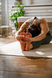© Jovo Jovanovic/Stocksy - Woman stretching arms and legs on mat while exercising at home