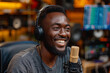 A confident and laughing black man enjoys a radio broadcast in a studio.
