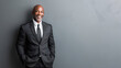 Happy african-american company leader CEO boss executive standing in front of company building. Portrait of a black businessman isolated on gray wall background.
