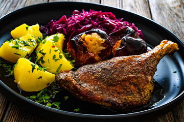 Wall Mural - Roast duck thigh with boiled potatoes, apples and red cabbage on wooden table
