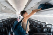 © Alvaro Lavin/Stocksy - Woman placing luggage in overhead bin.