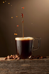 Wall Mural - Espresso coffee glass cup with splashes on a brown background.