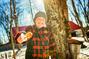 photo showing children tasting maple syrup with wooden spoon