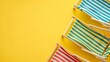 Striped beach chairs on a yellow background. Flat lay composition with place for text.