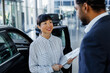 © Jovo Jovanovic/Stocksy - Asian executive discussing with male customer at dealership