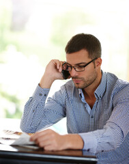 Man, home and phone call while reading an article, networking and newspaper for information. Serious male person, smile and app for conversation on morning, internet and story or weekend connection