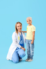 Sticker - Little Asian girl after chemotherapy with doctor on blue background. Childhood cancer awareness concept