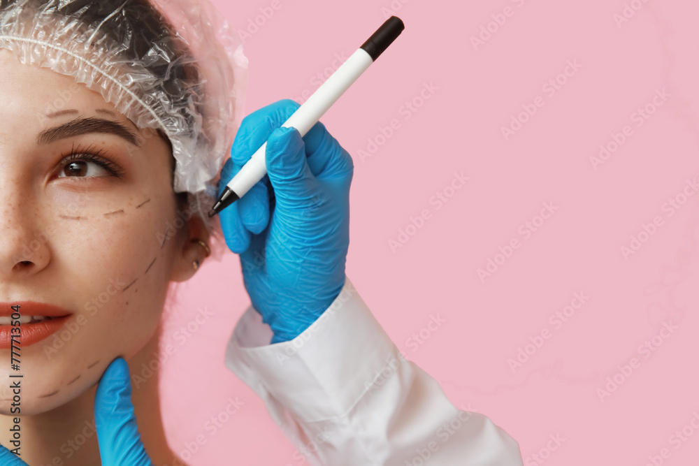 Plastic surgeon marking woman's face on pink background, closeup