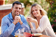 © peopleimages.com - Portrait, happy and couple eating breakfast in garden outside at table in morning. Married, man and woman on romantic getaway at house sitting on patio talking, coffee and care for relationship