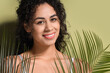 Young African-American woman with palm leaves on green background, closeup