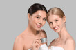 Beautiful women with jar of facial cream on grey background, closeup