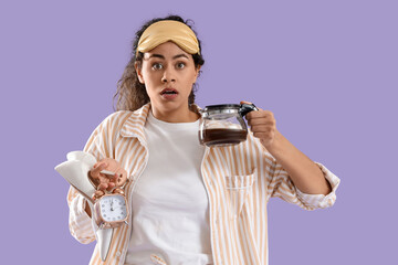 Wall Mural - Overslept young African-American woman in pajamas with heels and coffee pot on lilac background