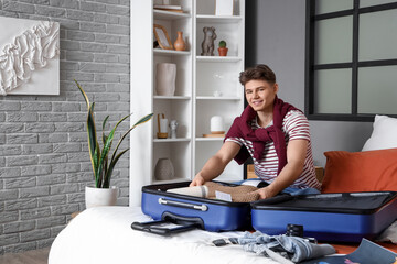 Poster - Male tourist unpacking suitcase in hotel room