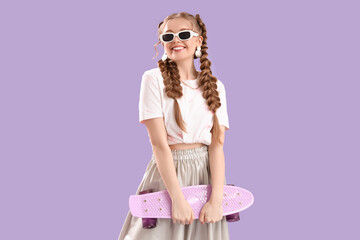 Poster - Happy smiling young woman with braids in sunglasses holding skateboard on lilac background