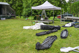 Fototapeta Tulipany - Pavilion for the sound system, tent poles and tarpaulins in bags for setting up an open-air music festival on the meadow, copy space, selected focus