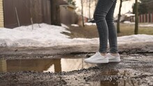 A Woman In Snow-white Sneakers Almost Falls Into A Puddle. Stops In Time And Goes Around Her