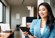 © Miklos - A young woman in a business suit standing in an office with a tablet in her hand.