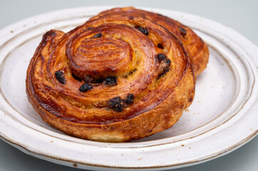 Breakfast in bakery with fresh baked coffee buns sweet pastry with raisins, morning food close up