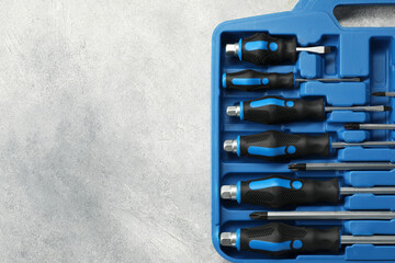 Poster - Set of screwdrivers in open toolbox on light grey textured table, top view. Space for text