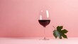 Romantic composition with red wine glass and leaf shadow on pastel pink background on a sunny day. Trendy, minimal party concept.