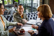 © Jovo Jovanovic/Stocksy - Diverse business team discussing in meeting at cafe