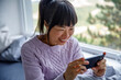 © Jovo Jovanovic/Stocksy - Happy woman playing game on smart phone at home