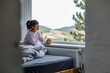 © Jovo Jovanovic/Stocksy - Woman enjoying coffee while relaxing by window on bed