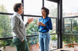 © ALTO IMAGES/Stocksy - Multiracial coworkers chatting near panoramic window