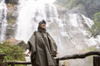 © Alvaro Lavin/Stocksy - Woman in raincoat near waterfall.