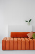 © Alina Hvostikova/Stocksy - Comfortable orange armless sofa with round back placed at home