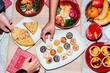 © Lucas Ottone/Stocksy - Hands reaching for food at dinner table