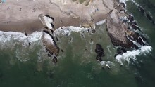 Aerial Shot Tracking Along The Coastline As Waves Hit Large Rock Formations At A Malibu Beach