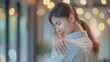 © nilanka - Asian young woman experiencing shoulder and back pain at home. painfully facial expressions as she tries to reach the spot on the back of her hand. Generative ai