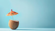 Coconut with cocktail umbrella on a blue background, summer concept.