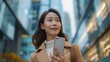 asian happy businesswoman use smartphone while she standing on sidewalk in the city