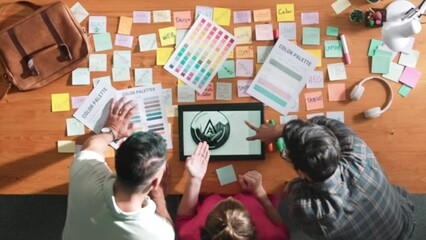 Wall Mural - Top view of smart designer holding color palette while project manager looking at design and choosing color for program. Professional businesswoman taking a note while design creative logo. Symposium.