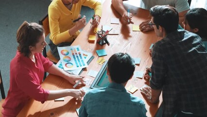 Top view of manager writing idea on sticky notes and explain idea about web design. Professional marketing team or programmer brainstorming idea while looking at tablet with color palette. Symposium.