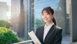 © tenpadasi - 朝のオフィスビル・オフィス街の笑顔の日本人女性会社員ポートレート　ビジネス・仕事・新入社員・若者　　