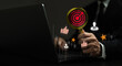 A man is holding a magnifying glass over a laptop screen with a red target on it
