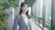 © tenpadasi - 朝のオフィス・オフィス街の笑顔の日本人女性会社員ポートレート　ビジネス・仕事・新入社員・若者　　太陽の光　レンズフレアとゴースト　緑の前ボケ