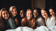 Cheerful beautiful multiracial female friends wearing silk robes enjoying champagne sitting on a bed in a hotel. Bridesmaids celebrating bachelorette party. Bride and bridesmaids